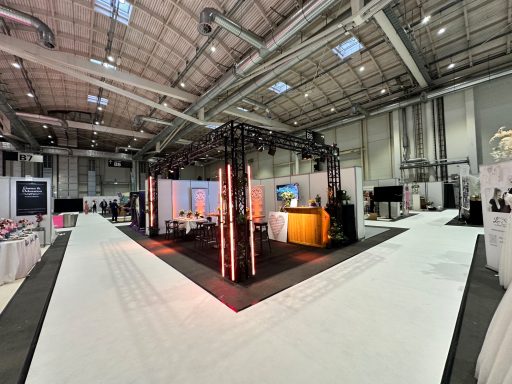 Messestand mit mehreren Ständen, beleuchtet und modern gestaltet, in einer großen Halle.